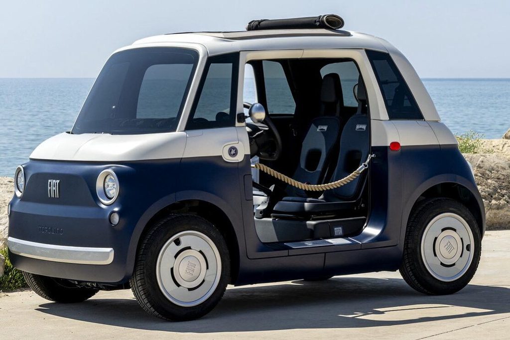 Fiat Topolino elettrica bicolore blu e bianca con tetto in tela, vista di tre quarti sul lungomare